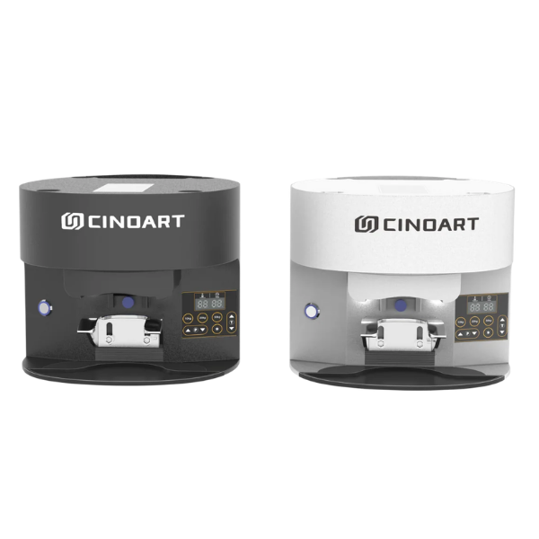 Two Cinoart cylindrical countertop cafe automatic coffee tamper machines shown side by side on a plain white background, one in black and one in white, both with front control panels and the CINOART logo visible on top.
