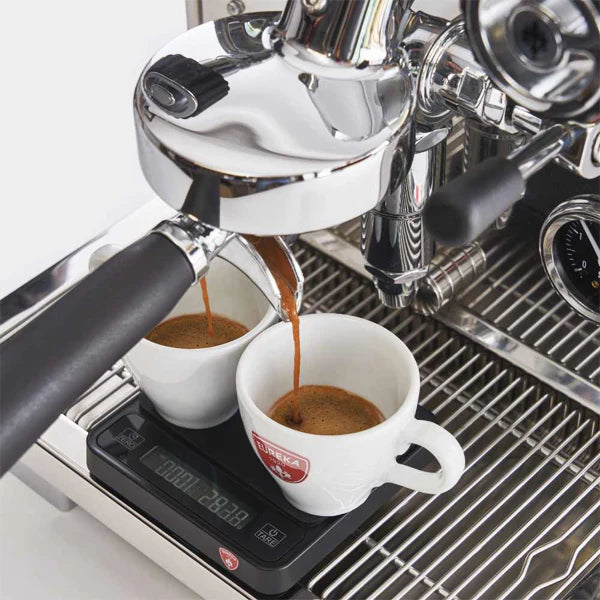 Espresso machine pouring coffee into two white cups with a visible brand logo.