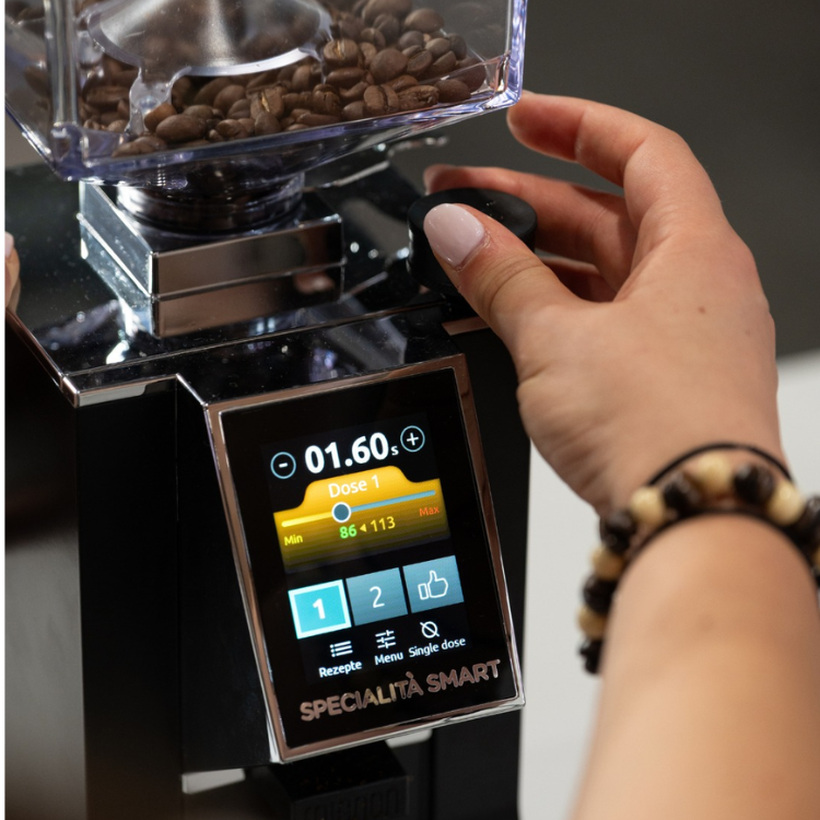 Hand adjusting a coffee grinder with a digital display, featuring the model name 'Specialita Smart'.
